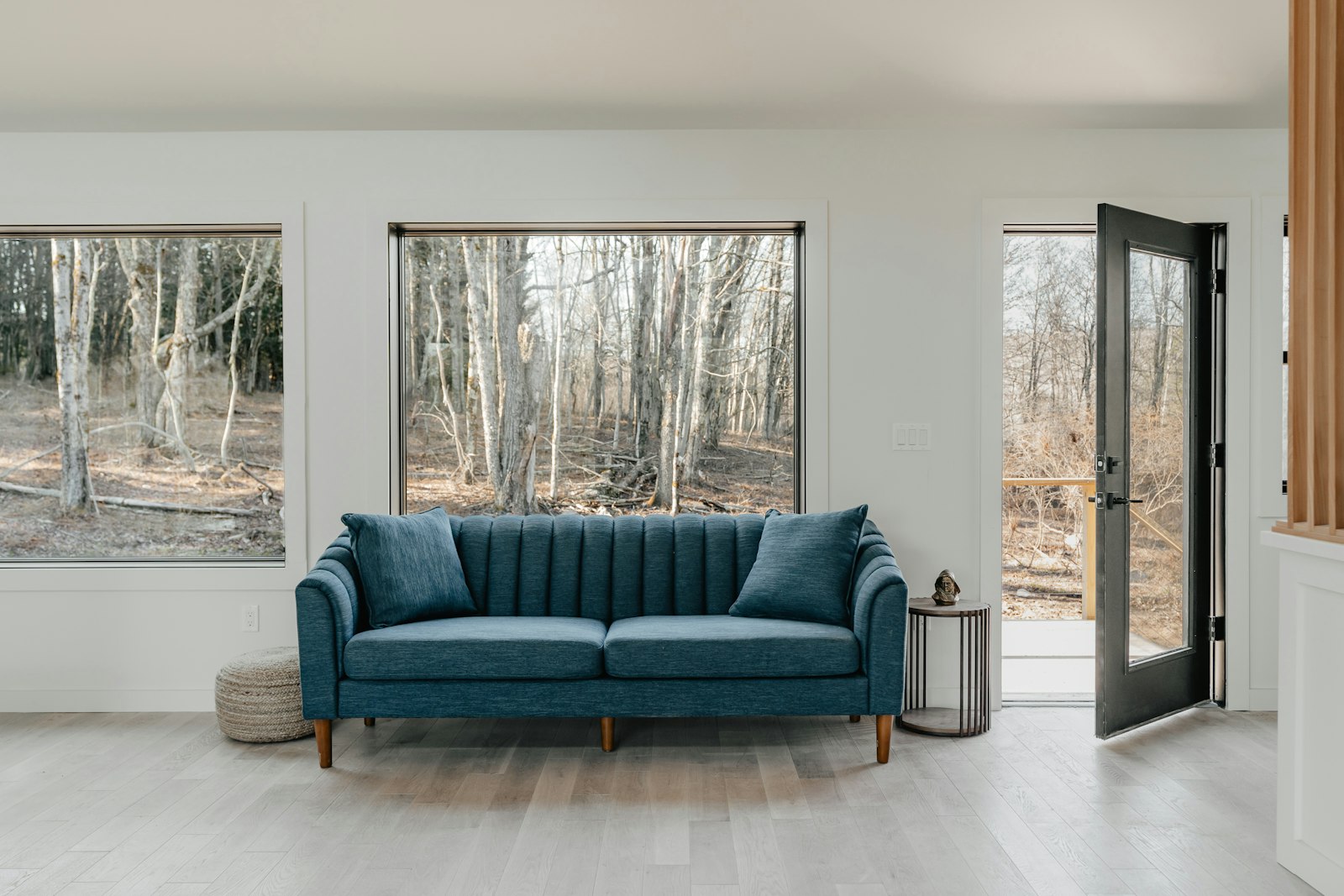 Blue velvet sofa in a bright living room with white walls and light floor