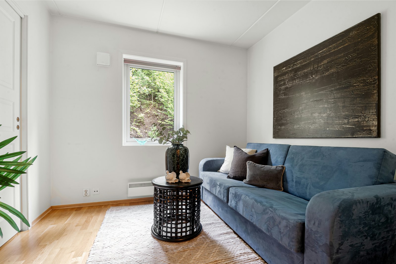 Living room with a blue sofa, wooden floor and white walls
