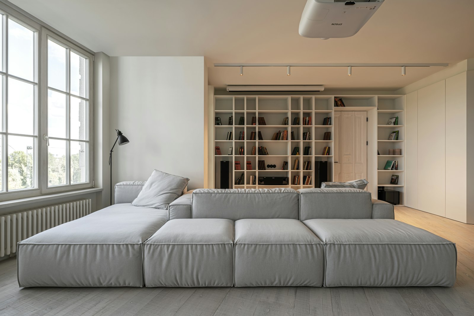Bright living room with a gray modular sofa and white bookshelves