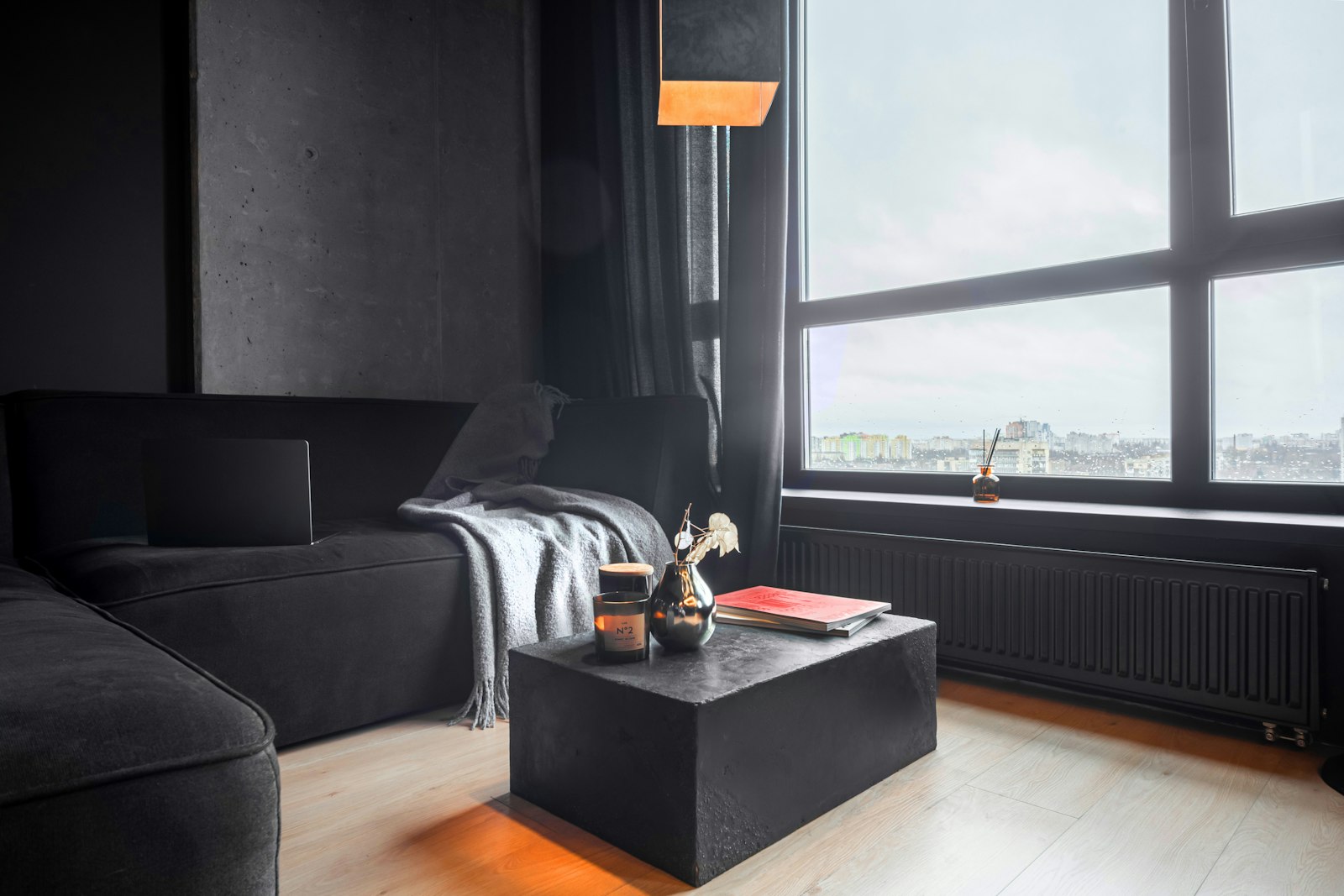 Minimalist living room with a graphite sofa against a dark wall with framed art