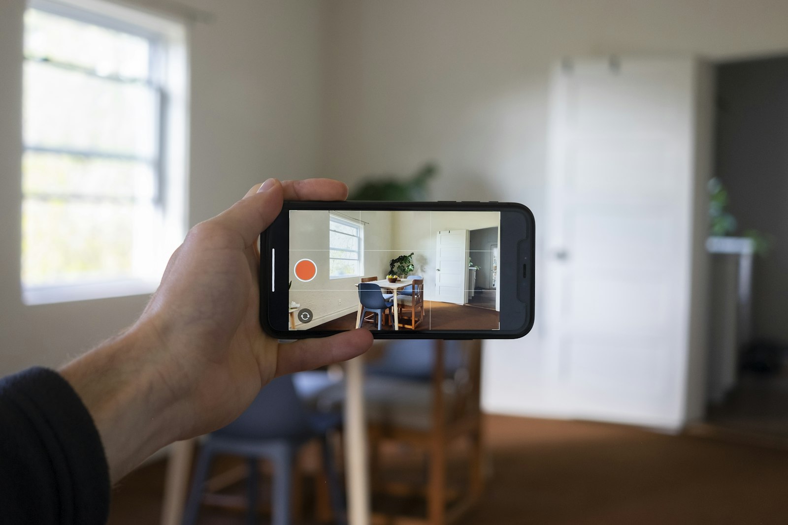 Hand holding a phone to photograph a bright empty room