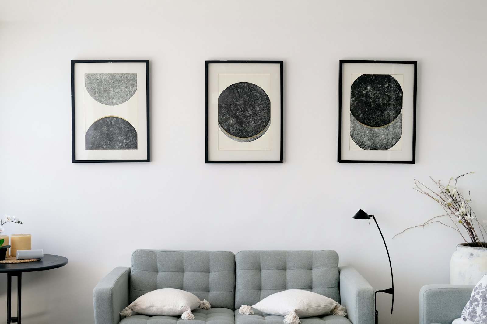 Soft gray wall with three framed prints above a pale gray sofa