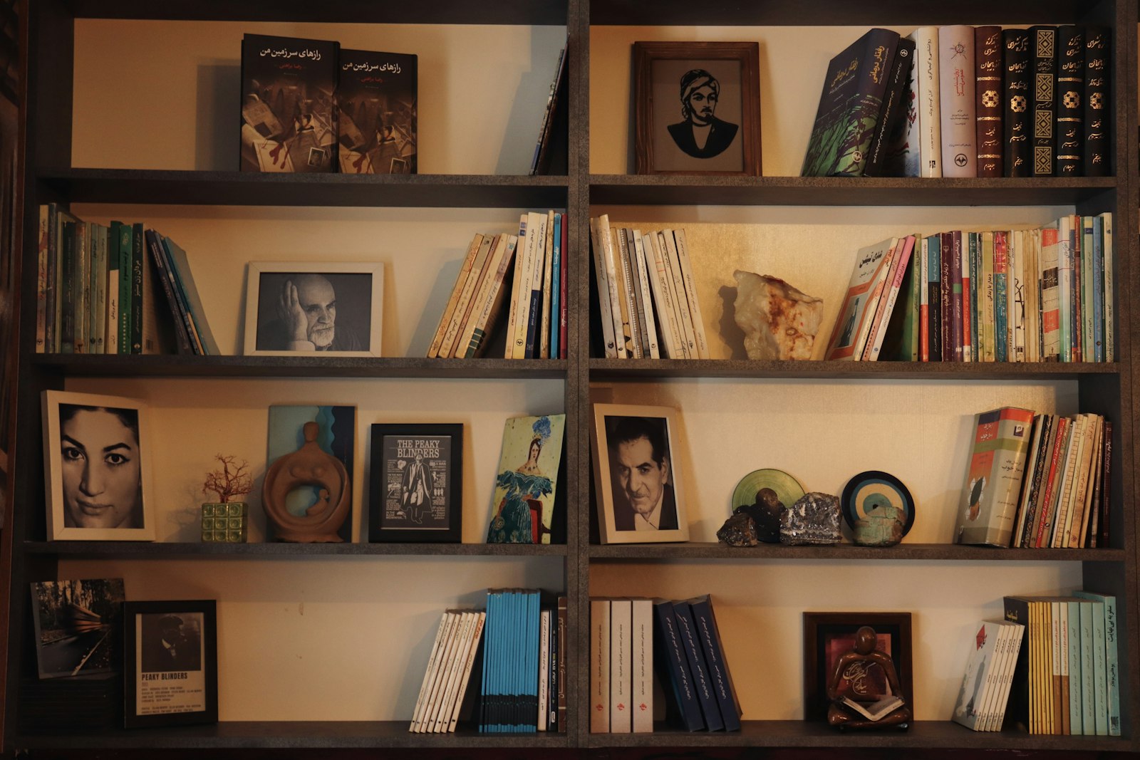 Warm wooden bookshelves with books and framed portraits